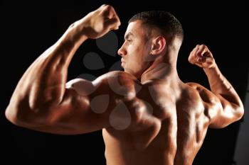 Male bodybuilder flexing muscles, side view