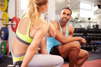Young woman and man talking at a gym
