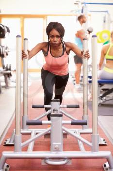 Young woman working out using equipment at a gym, vertical