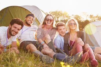 Group Of Friends Relaxing Outside Tents On Camping Holiday