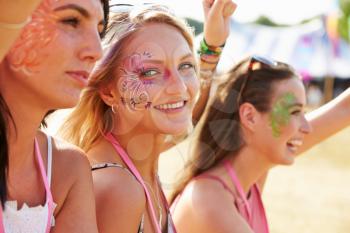 Three girl friends at a music festival, one turned to camera