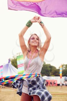 Blonde woman dancing with hula hoop at a music festival, vertical