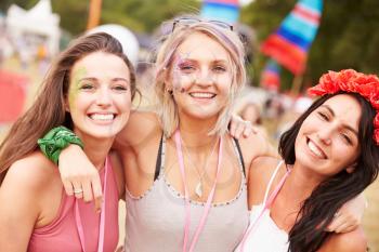 Girl friends with arms around each other at a music festival