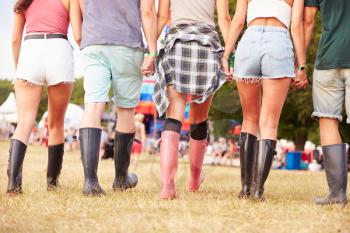 Friends walking together at a music festival site, back view