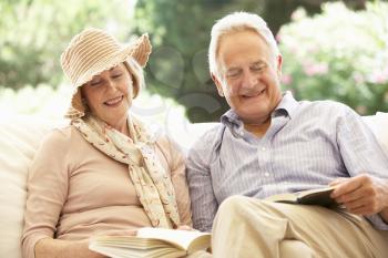 Portrait Of Senior Couple Relaxing On Sofa Reading Together