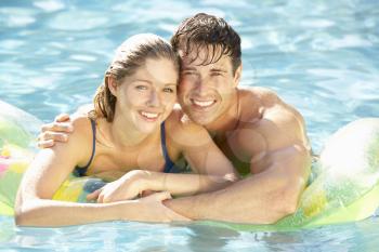 Portrait Of Young Couple Relaxing In Swimming Pool