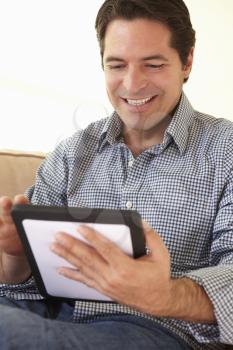 Hispanic Man Using tablet computer At Home