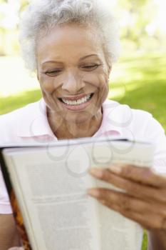 Senior African American Woman Reading Magazine In Park 