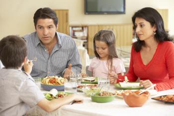 Young Hispanic Family Enjoying Meal At Home