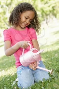Young African American Girl With Watering Can In Park