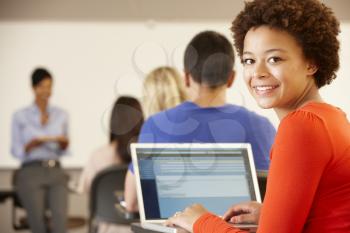 Mixed race teenage girl using laptop in class