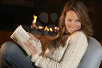 Woman reading in front of fire at home
