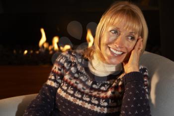 Mature woman relaxing in front of fire at home