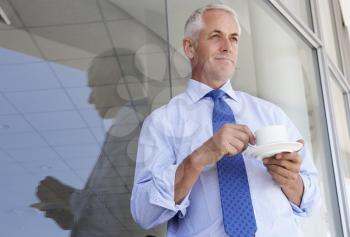 Mature Businessman Standing Outside Modern Office Drinking Coffee