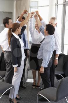 Group Of Businesspeople With Arms Raised At Company Seminar