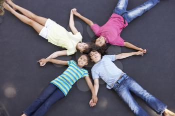 Overhead View Of Group Of Children Lying On Trampoline Together