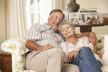 Retired Senior Couple Dozing On Sofa At Home Together
