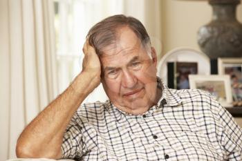 Unhappy Retired Senior Man Sitting On Sofa At Home