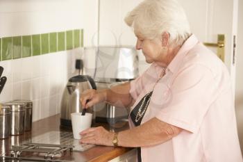 Retired Senior Woman In Kitchen Making Hot Drink