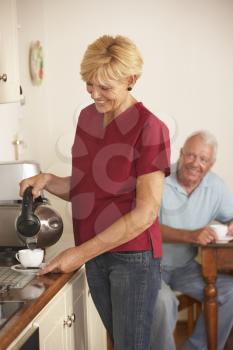 Home Help Sharing Cup Of Tea With Senior Male In Kitchen