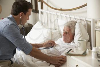 Doctor Examining Senior Male Patient In Bed At Home