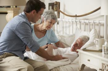 Doctor On Home Visit Discussing Health Of Senior Male Patient With Wife