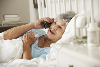 Sick Senior Woman In Bed At Home Talking On Phone