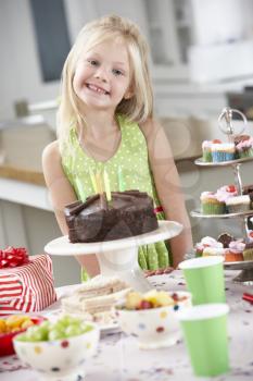 Young Girl Standing By Table Laid With Birthday Party Food
