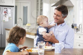 Father, Son And Baby Daughter Having Meal In Kitchen Together