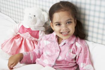 Young Girl Wearing Pajamas In Bed Reading Book