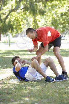 Young Man Working With Personal Trainer In Park