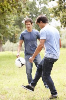 Two Young Men Playing With Soccer Ball In Countryside