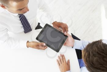 Overhead View Of Two Businessman Working At Desk Together With Digital Tablet