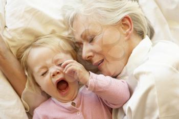 Grandmother Cuddling Granddaughter In Bed