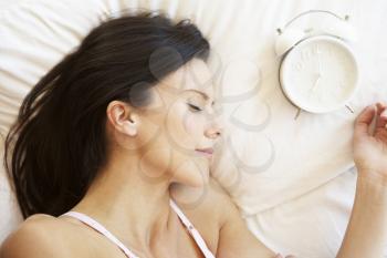 Woman Sleeping In Bed With Alarm Clock