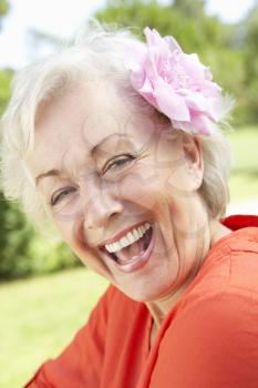 Head And Shoulders Portrait Of Smiling Senior Woman With Flower In Hair