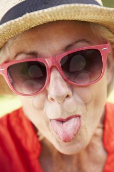 Head And Shoulders Portrait Of Senior Woman Poking Out Tongue