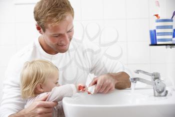 Father And Daughter In Bathroom Brushing Teeth