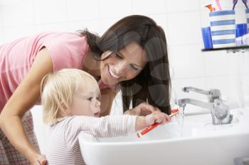 Mother And Daughter In Bathroom Brushing Teeth