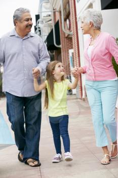 Senior Couple With Granddaughter Carrying Shopping Bags