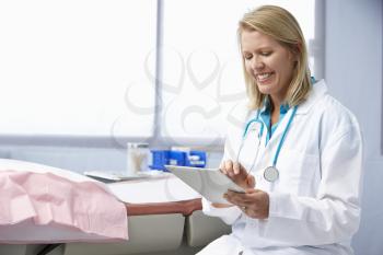 Female Doctor In Surgery Using Digital Tablet