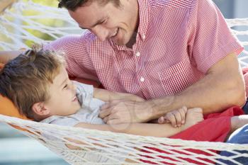 Father And Son Relaxing In Garden Hammock Together