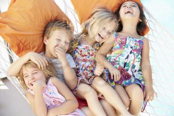 Four Children Relaxing In Garden Hammock Together
