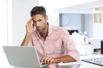 Stressed Man Working At Laptop In Home Office