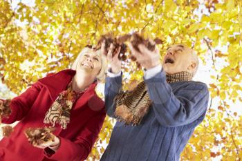 Senior Couple Throwing Leaves Into Air