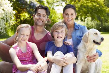 Portrait Of Family With Dog  Relaxing In Summer Garden