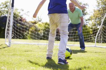 Grandfather And Grandson Playing Football Together