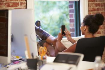 Businesswoman On Mobile Phone Relaxing In Modern Office