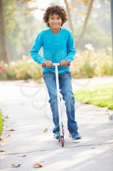 Young Boy Riding Scooter In Park