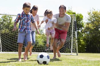 Family Playing Football In Garden Together